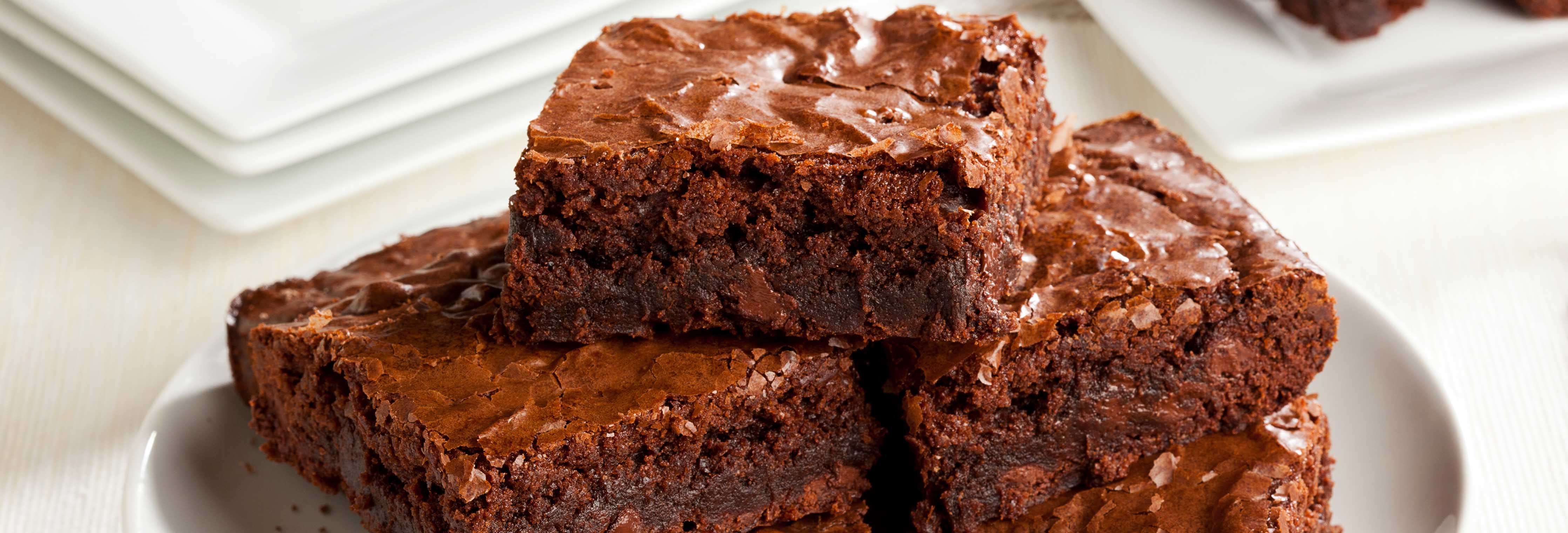 Stack of chocolate sweet potato protein brownies on a white plate