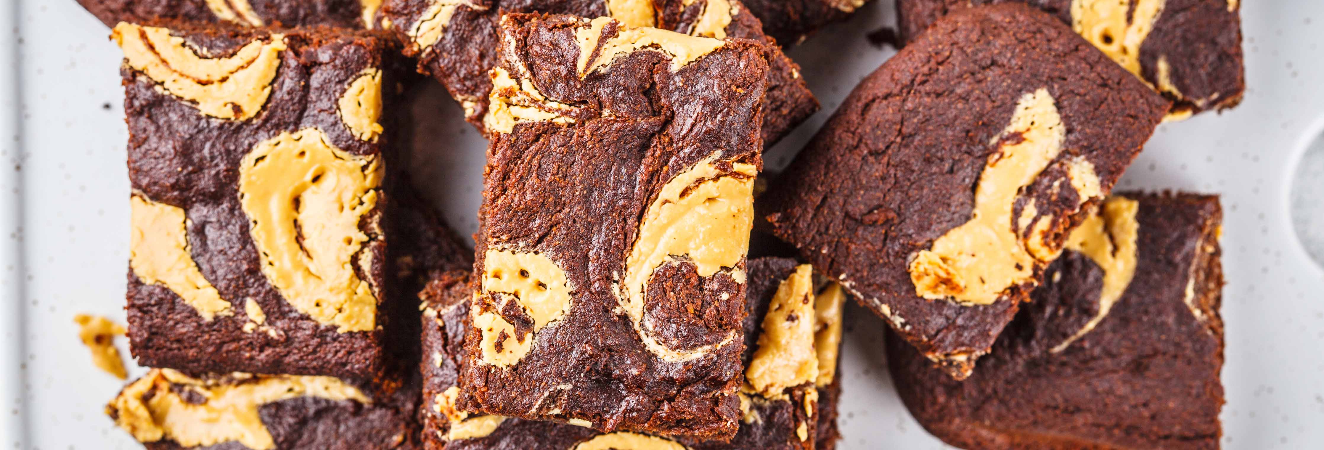 Top-down view of peanut butter crumble brownies showing chocolate squares with peanut butter swirls on a light speckled surface