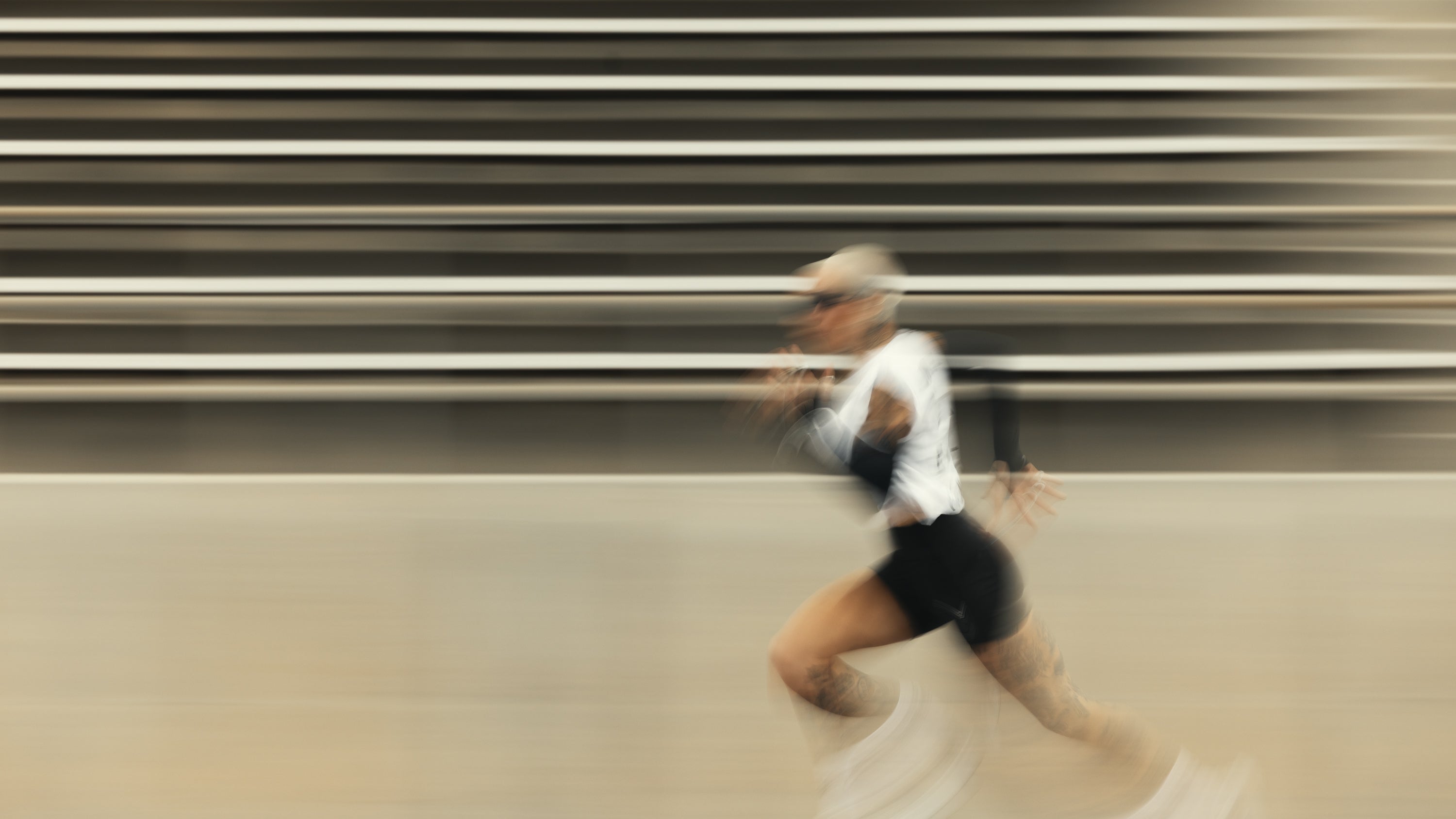 Athlete sprinting past stadium bleachers with motion blur suggesting a high-energy workout