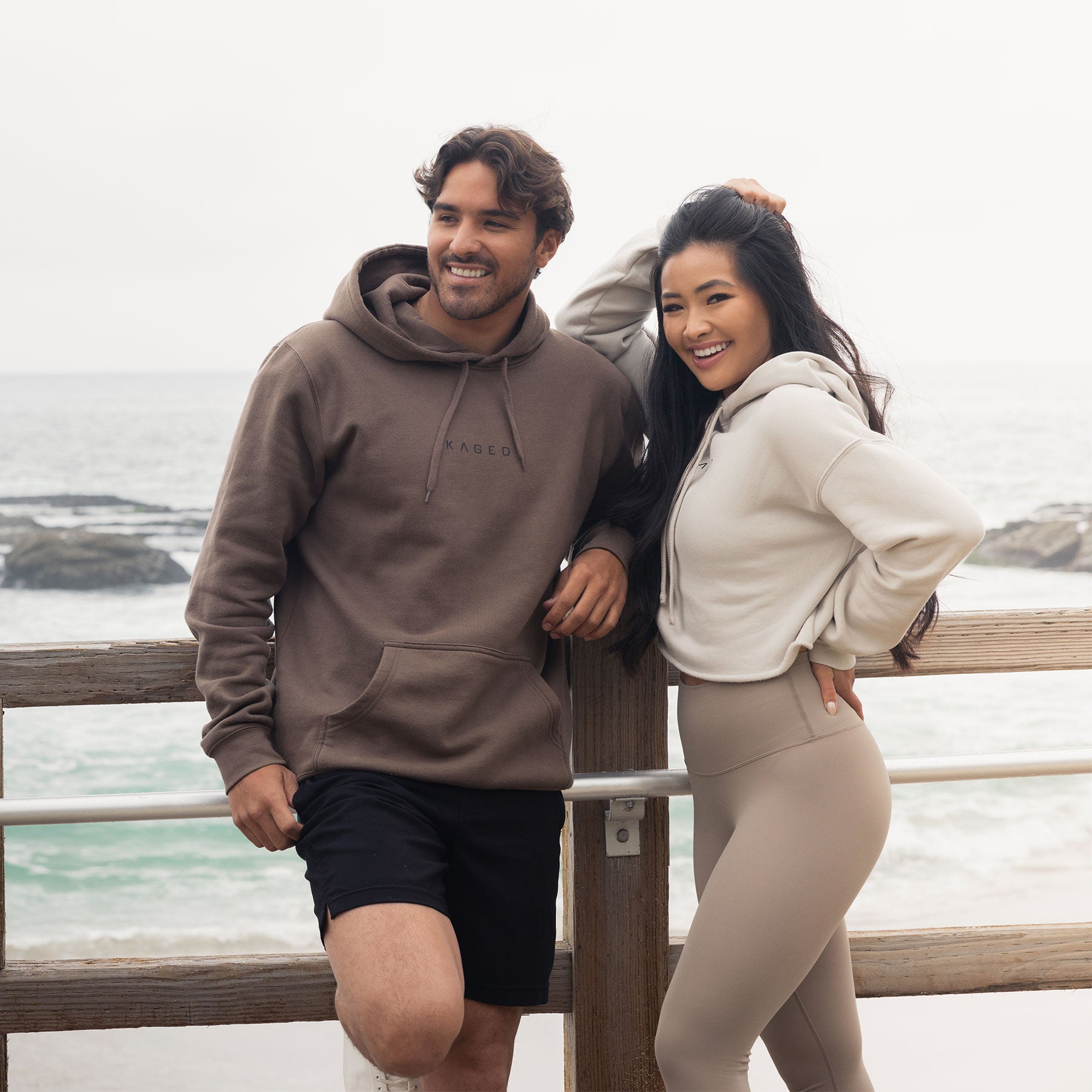 Three-quarter view of walnut Never Stop Evolving unisex hoodie on male model showing KAGED logo, hood, and kangaroo pocket #color_walnut