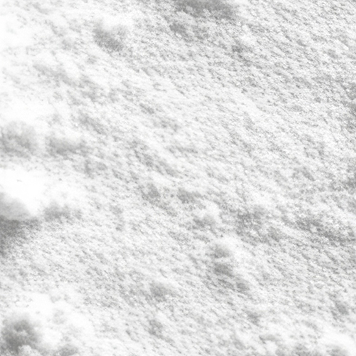 Close-up of micronized creatine monohydrate powder showcasing fine, easily mixable texture on a white background