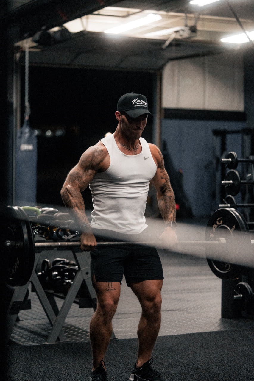 Muscular man performing a barbell deadlift in a dim gym, demonstrating intense weightlifting and training