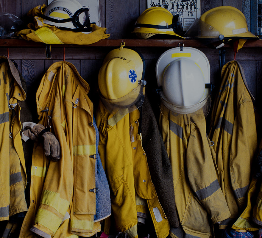 Yellow firefighter jackets and helmets hanging in a station locker, representing first responders