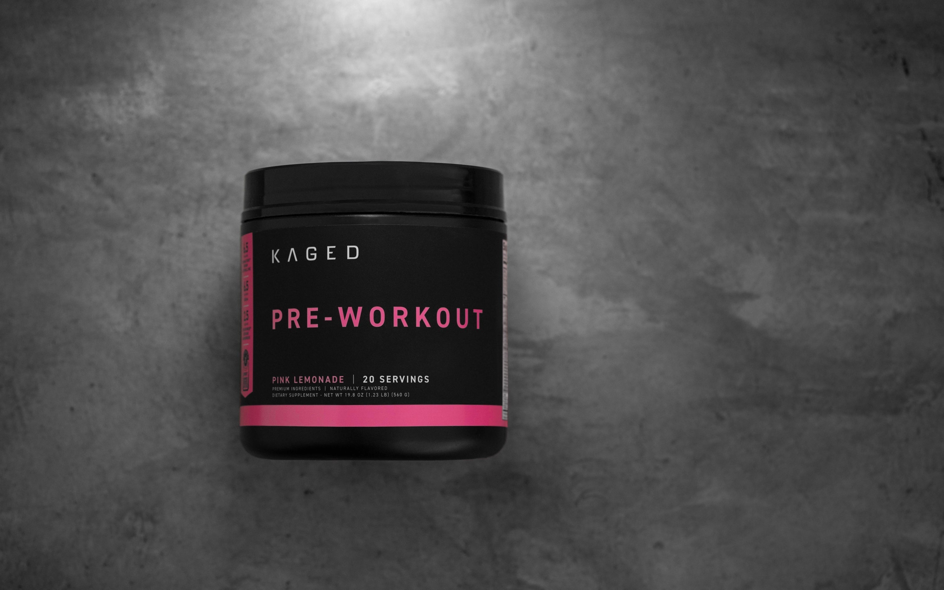 Front view of KAGED Pre-Workout tub, Pink Lemonade, 20 servings, bold PRE-WORKOUT label and pink accent on gray background