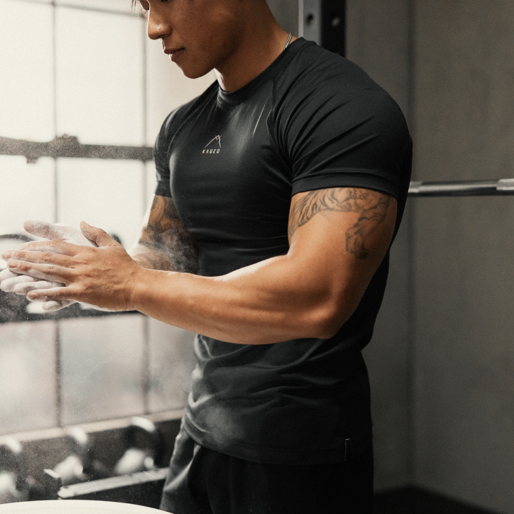 Three-quarter view of Ascent Performance Tee on male model showcasing slim athletic fit and moisture-wicking black fabric in a gym