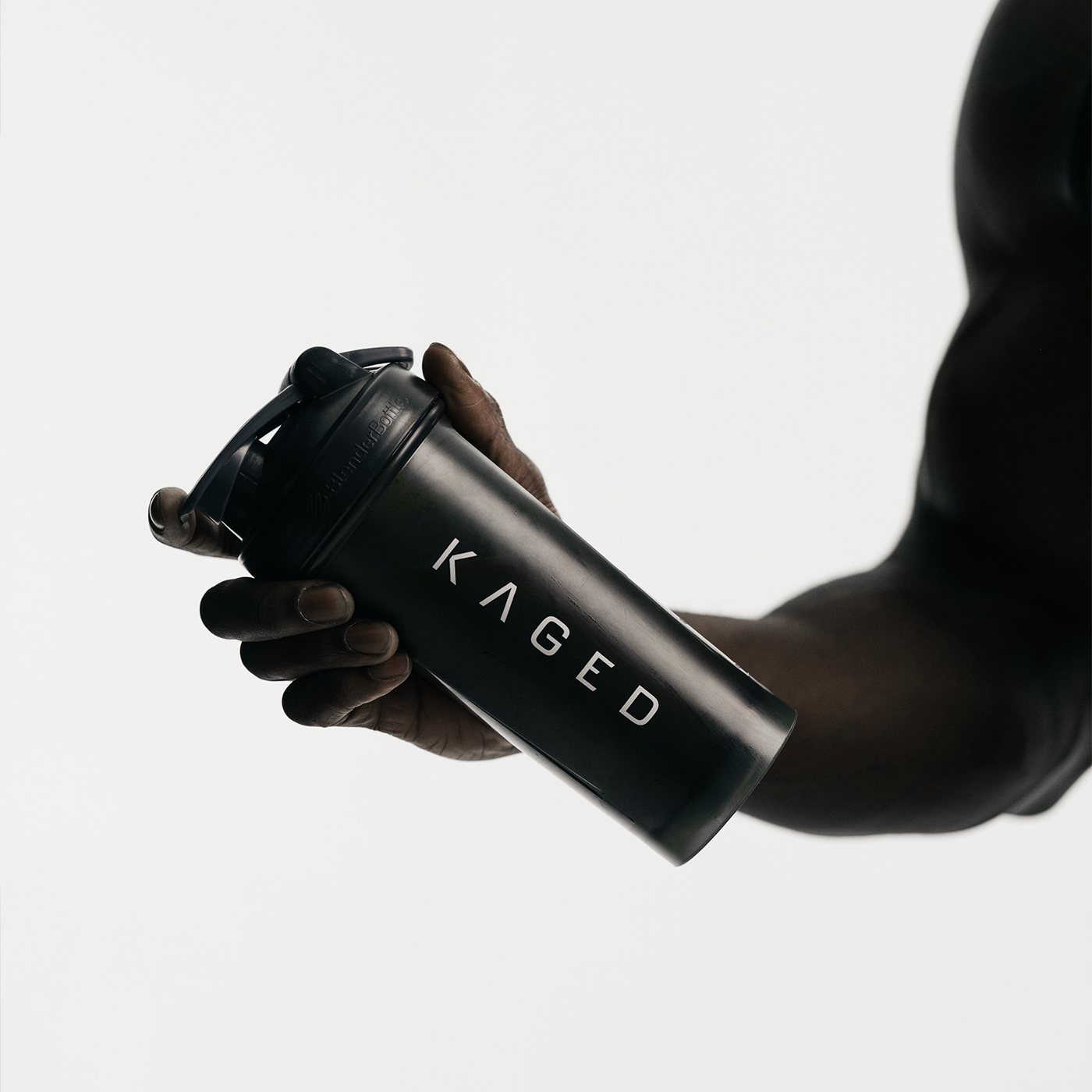 Angled view of Blender Bottle Classic 28 oz showing SpoutGuard lid, carry loop, and KAGED logo against a white background while held in a hand
