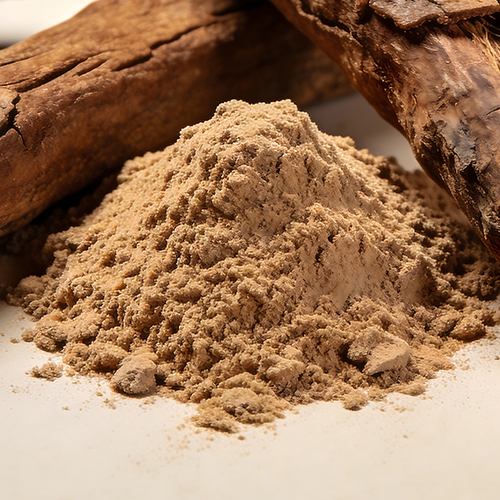 Close-up of LJ100® Tongkat Ali powder mound with Tongkat Ali root pieces in the background on a white surface