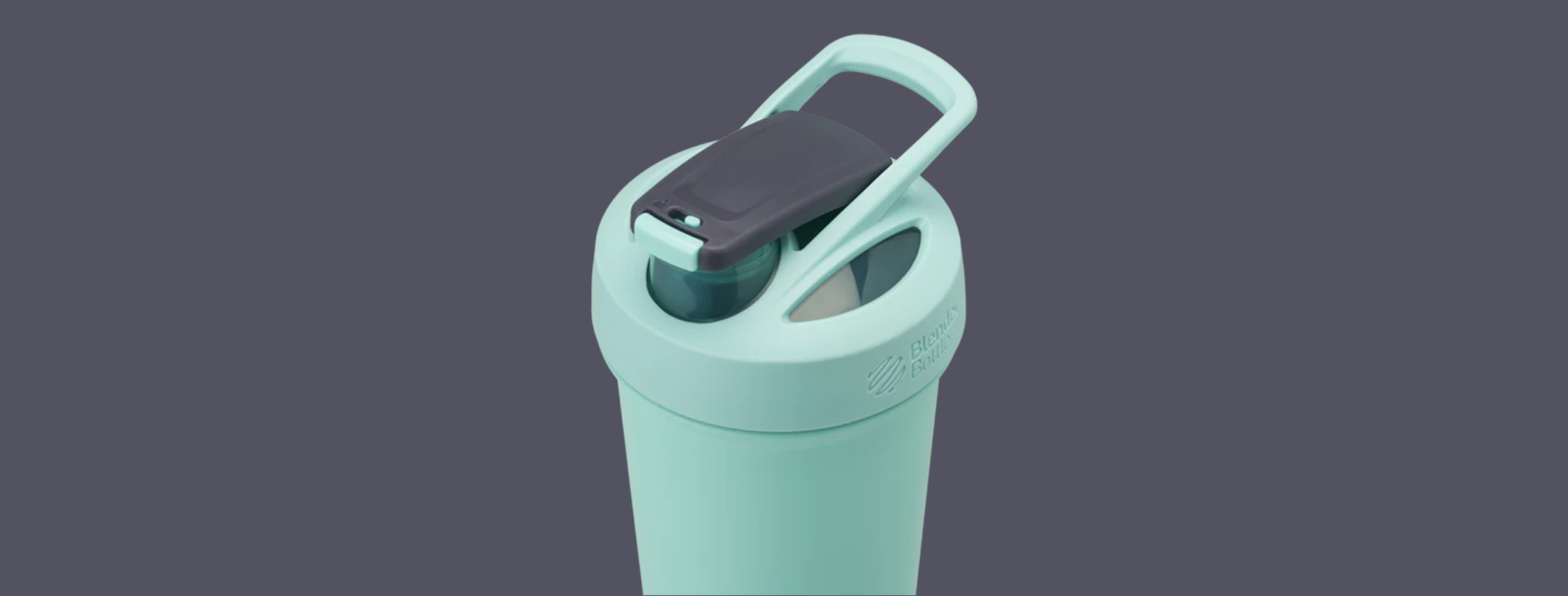 Angled top view of mint stainless steel shaker showcasing hinged flip-spout lid with carry handle on dark gray background