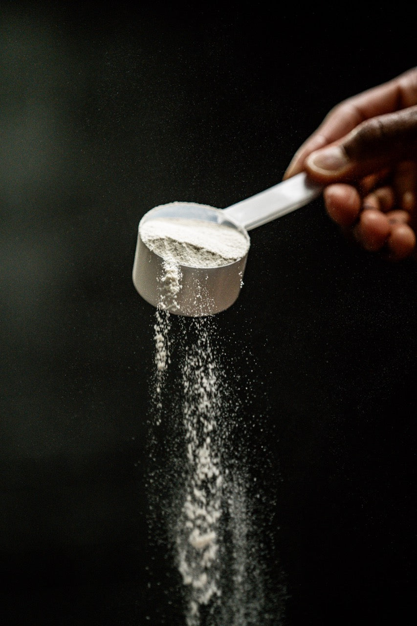 Close-up of Kaged BCAA powder in a scoop showcasing fine powder pouring against a dark background