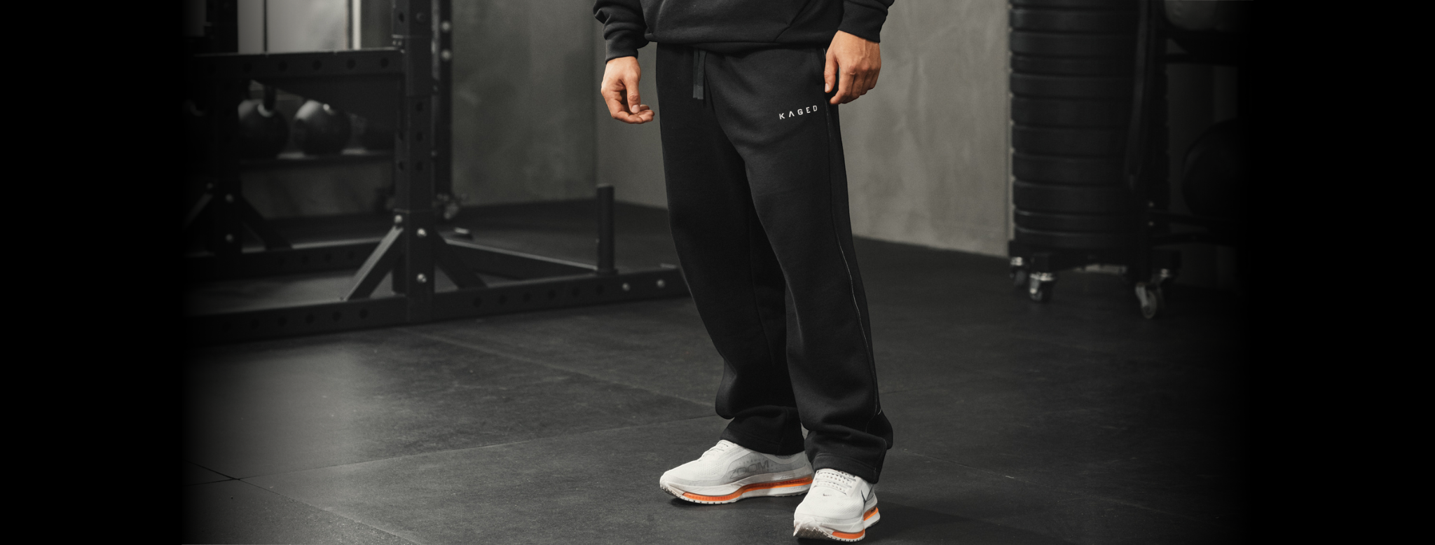 Front view of Ascent straight leg sweats showcasing straight-leg fit with KAGED logo on left thigh and gym background